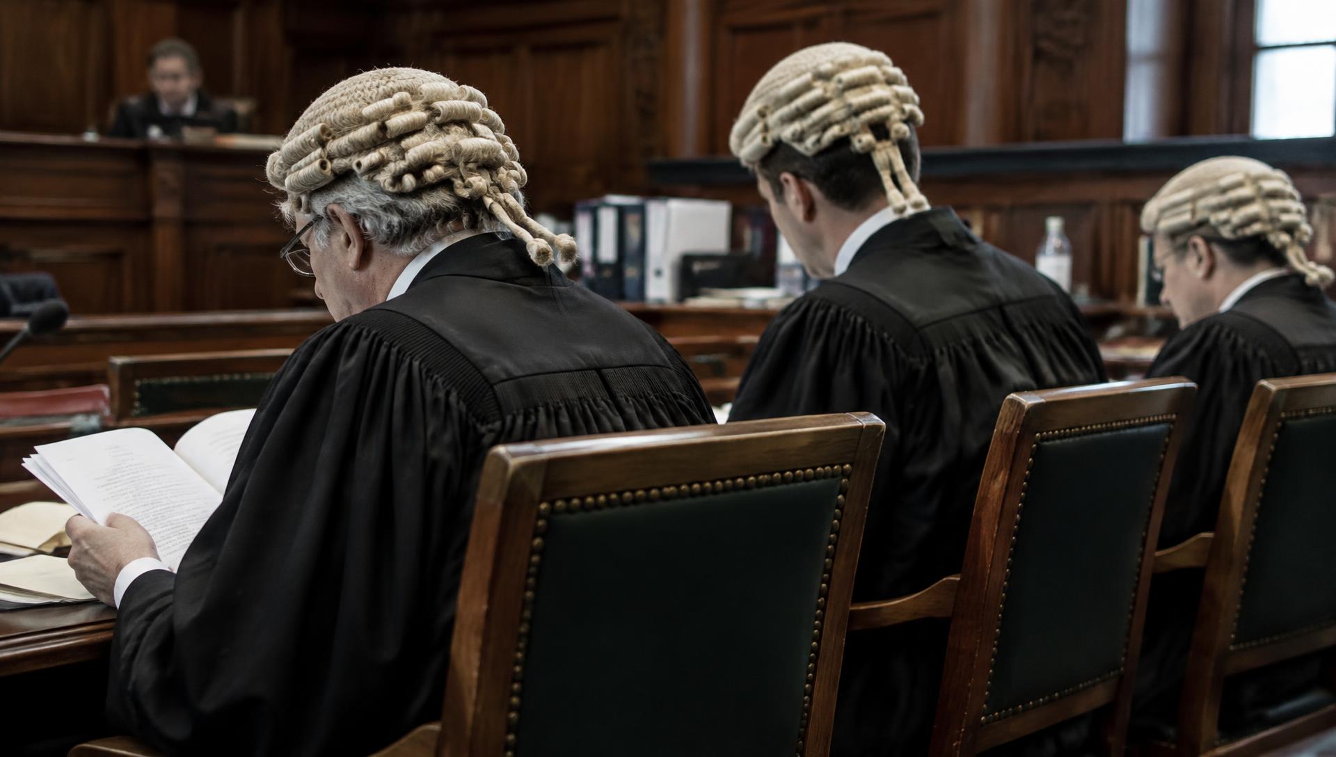 Barristers in wigs and gowns reviewing papers in court